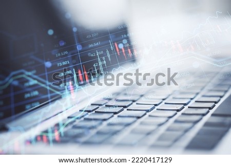 Close up of laptop computer keyboard with creative candlestick forex chart index hologram on blurry background. Trade, business market and finance analysis concept. Double exposure