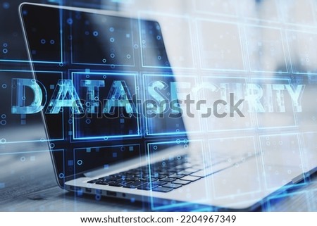 Close up of laptop with creative blue cubes data security text hologram on blurry background. Technology, secure and information protection concept. Double exposure