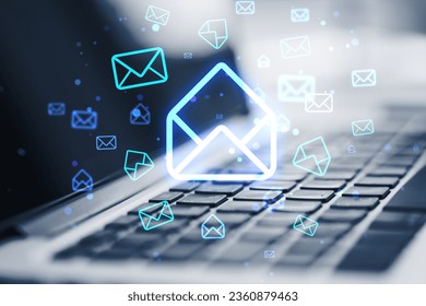Close up of laptop on desk with glowing email letter icons on blurry background. Communication and business message concept