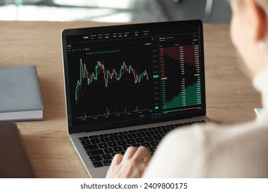 Close up laptop screen view with stocks charts and graphs over shoulder of female crypto trader, analyze financial stock, makes trade market research, buy or sell cryptocurrency, review risk or profit - Powered by Shutterstock