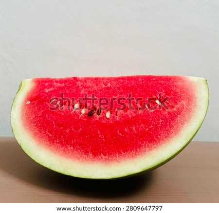 Close up of a large half circle slice of fresh red watermelon on a wooden table