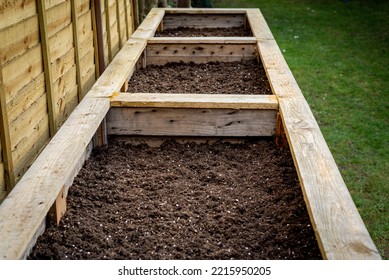 Close Up Of Large Wooden Planter Vegetable Box Containers In Backyard Garden Filled With Fresh Organic Soil Ready For Planting Seeds And Vegetable Plants.