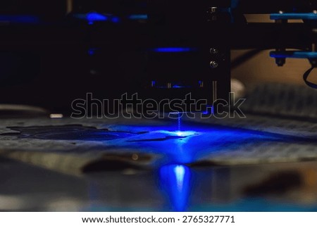 Close up of laser cutting paronite. Powerful blue laser burning complex gasket shape out of asbestos material. Smoke and sparks visible during precise manufacturing of industrial seals.