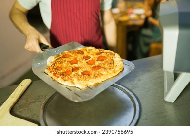 Close up of a latin man baking delicious homemade pizza in the oven for his friends in the oven at home - Powered by Shutterstock