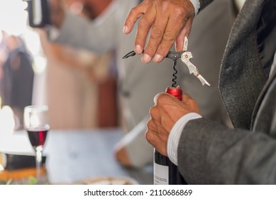 Close Up Of A Latin Man Opening A Bottle Of Red Wine With A Corkscrew