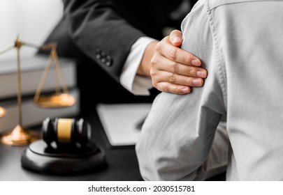 Close up of lawyer touching the shoulder client reassuring concern,  discuss make a deal agreement, sign contract, Judge gavel, brass scale, law firm office, law, and justice advice service.