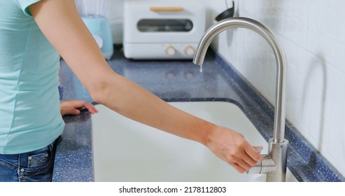close up of leaking faucet in kitchen - asian woman hand turn off water dripping from tap - Shutterstock ID 2178112803
