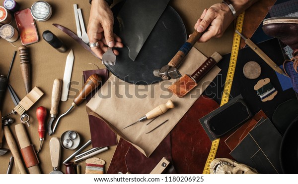 Close up of\
leather designer hands making custom made shoes working with\
genuine leather and hammer at a\
workshop.