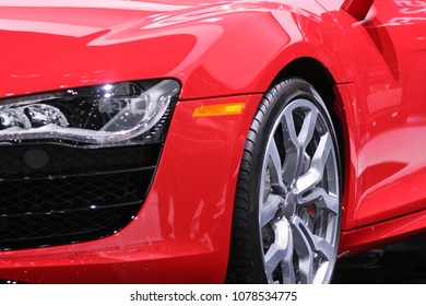 Close up of a left front corner of a red sports car.