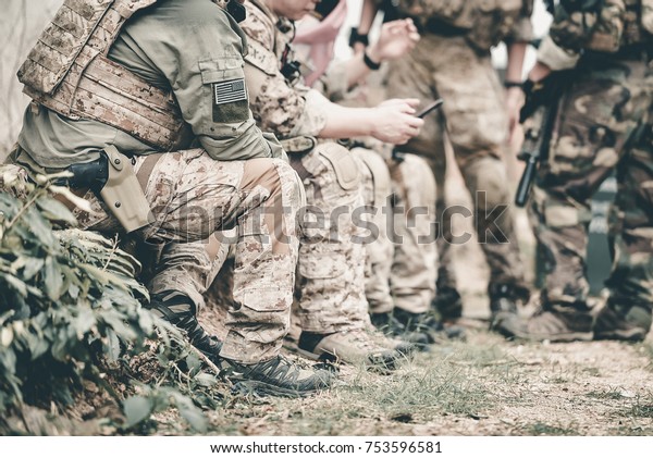 close up leg\
hunting, war, team army and people concept - young soldier, ranger\
or hunter with gun sitting in\
forest