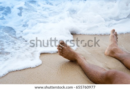 Close up leg of young man sitting on the beach,summer vacation concept