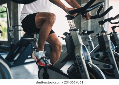 Close up legs of asian sportsman exercising on a bicycle in the gym, determination to cardio lose weight, makes her healthy. exercise bike man fitness sport concept. - Powered by Shutterstock