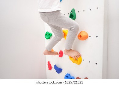 Close up of legs of little kindergarten boy having fun trying to climb on a small rock wall indoor at home, Physical, Hand and Eye Coordination, Sensory, Motor Skills development, Home workout concept - Powered by Shutterstock