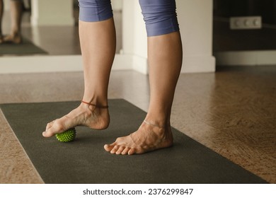 Close - up of the legs of a woman performing gymnastic exercises to correct flat feet during ball massage at home