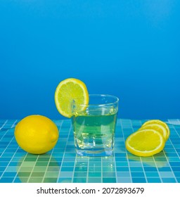 Close Up Lemon Juice With Slice Lemon On Glass Rim, And Fresh Lemon On Blue Tile Grid Table And Blue Background, Bartender Prepare Fruit Cocktail Or Fresh Juice For Drinking In Party At Bar