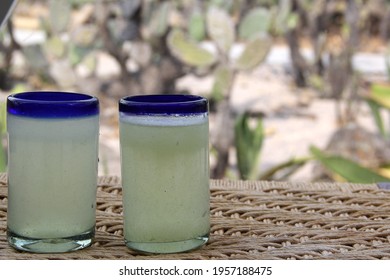 Close Up Lemonade In Blown Glass Glass On Table And Desert Vegetation In The Background, Glamping Drink Desert Mexico