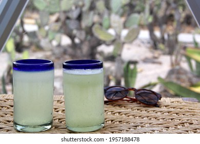 Close Up Lemonade In Blown Glass Glass On Table And Desert Vegetation In The Background, Glamping Drink Desert Mexico