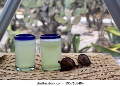 Close Up Lemonade In Blown Glass Glass On Table And Desert Vegetation In The Background, Glamping Drink Desert Mexico