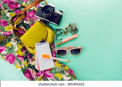 Close up lifestyle photo of hipster student accessories . Still life of random objects of modern girl / woman. Leather bag, camera, Sunglasses, paper notepad, Aerial view. Sunny summer colors.