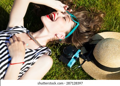 Close Up Lifestyle Portrait Of Cheerful Brunette Hipster Girl Going Crazy Making Funny Face And Showing Her Tongue.Laying On The Ground And Laughing.Bright Colors,urban Street Background.accessories