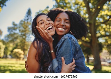 Close up lifestyle portrait of diverse multiracial happy best friends hugging each other and laughing in the park - Powered by Shutterstock