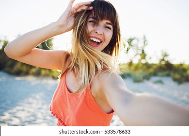 Close up lifestyle portrait of happy laughing  woman on beach making self portrait on camera. True emotions. 