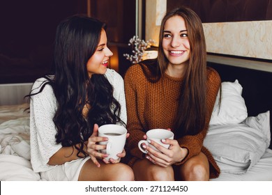 Close Up Lifestyle Portrait Of Two Best Friends Talking And Laughing Sitting On  Bed At Home. Enjoying Sunny Morning .