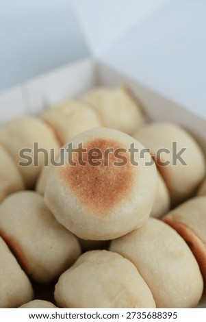 A close up of light fluffy bread rolls piled in a box with golden tops, perfect for bakery, breakfast, or snack imagery conveying fresh comfort daily.