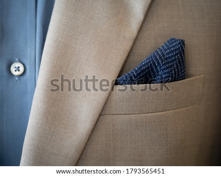 Close up of light grey jacket with ticket pocket , blue shirt detail