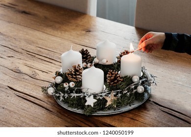 Close Up Of Lighting The First Candle On Advent Wreath On The First Sunday In December. Celebrating Christmas Holidays, Swiss Tradition. Crop Hand Holding The Safety Matches To Light The Candle.