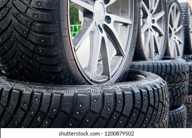 A Close Up Of A Lined Winter Studded Wheels Set Outdoors. Close Up Of The Studs And Protectors On Tires Installed On The Street. Winter Tires Positioned Outdoors. Rows Of Exposed Snow Tires.