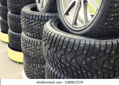 A Close Up Of A Lined Winter Studded Wheels Set For Sale. Close Up Of The Studs And Protector On Tires Installed On The Street. Winter Tires Positioned Outdoors. Rows Of Exposed Snow Tires.