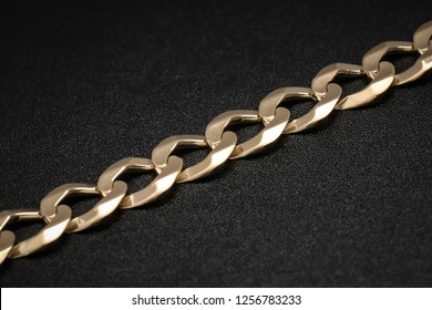 Close Up Of The Links Of A Mens Cuban Link Solid Gold Bracelet On Black Textured Background