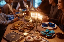 Close Up Of Lit Candles In Menorah With Jewish Multigeneration Family Celebrating Hanukkah At Dining Table.