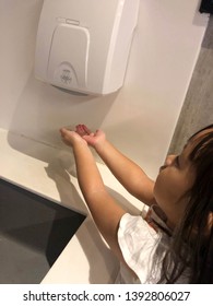 Close Up Of Little Asian Girl Using Hand Dryer In The Toilet