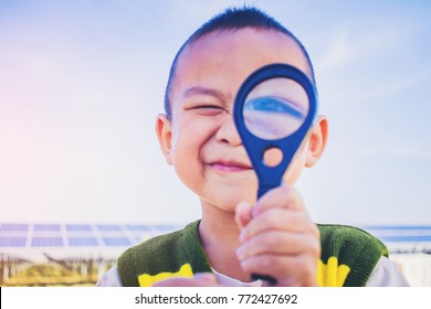 Close Up Of Little Boy With Smile Looking Through Magnifying Glass.