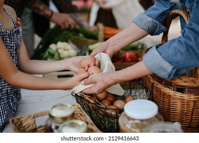 Close up of little girl buying organic eggs outdoors at local farmers market. - Shutterstock ID 2129416643