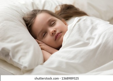 Close Up Little Girl Put Head On Cupped Hands Lying On Soft Pillow Covered With White Fresh Blanket Fall Asleep, Kid Sleeps Sweetly In Bed Having Healthy Day Nap, Relaxation Of Brain And Body Concept