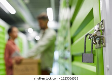 Close Up Of Lock On Self Storage Unit With Blurred Shape Of Couple In Background, Copy Space