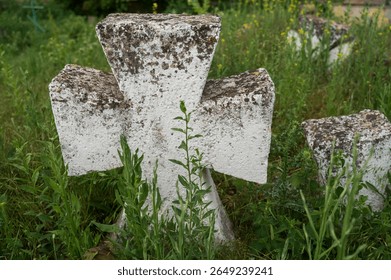 Close up of lonely ancient stone carved christian cross in old cemetery among grass. Nameless gravestone. Picture of gravestones in peaceful church yard. Tombstone in old european cemetery. - Powered by Shutterstock - Get 15% off with code: PIKWIZARD15
