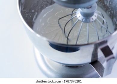 Close Up Look Into A Stand Mixer With Creamy Icing Being Blended Using A Whisk Attachment.