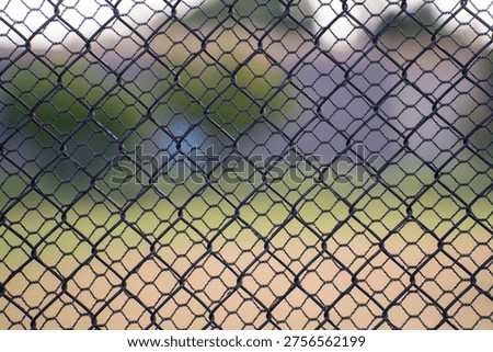 close up of looking through two chain link fences of different sized shapes or holes geometrical shapes inside each other two layers of fencing fir protection security and anti theft  
