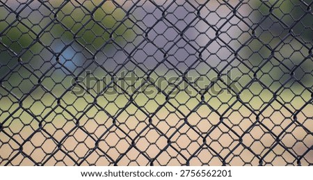 close up of looking through two chain link fences of different sized shapes or holes geometrical shapes inside each other two layers of fencing fir protection security and anti theft  