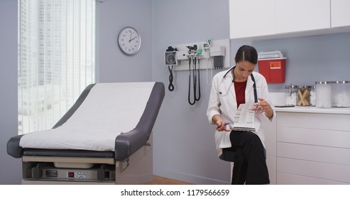 Close Up Of Lovely Latina Doctor Reviewing Patients File Indoors Medical Clinic