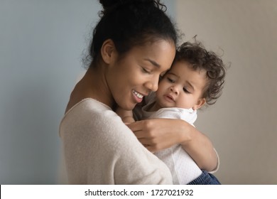 Close Up Of Loving Biracial Young Mom Hug Cuddle Little Ethnic Infant Toddler, Happy Caring African American Mother Embrace Lull Small Baby Girl Child, Enjoy Tender Moment, Childcare Concept