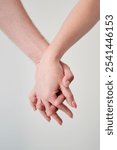 Close up of loving couple holding hands. Intertwined fingers over white background.