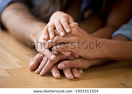 Close up of loving family stack hands on warm floor together show support and unity, caring parents join arms with child express devotion loyalty understanding. Bonding, good relationships concept