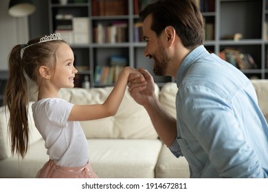 Close Up Loving Father Holding Adorable Little Daughter Hand, Pretty Girl Wearing Princess Dress And Diadem Playing With Dad, Family Enjoying Tender Moment, Leisure Time At Home Together