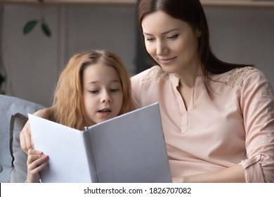 Close Up Loving Mother And Pretty Little Girl Child Reading Book Together, Sitting On Cozy Couch In Living Room, Caring Mom Teaching Preschool Daughter, Family Enjoying Leisure Time At Home