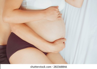 Close up of loving pregnant couple on bed (warm tone) soft focus concept for Sex during pregnancy